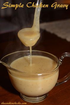 a spoon pouring sauce into a glass bowl filled with gravy on top of a wooden table