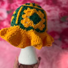 a crocheted yellow and green hat on top of a white mannequin head