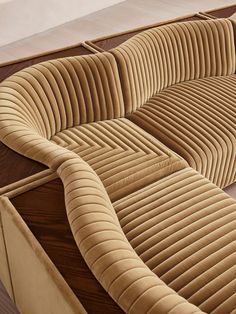 the curved couch is made out of wood and has an interesting pattern on it's sides