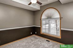 an empty living room with a ceiling fan and carpeted flooring in front of the window