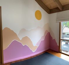 an empty room with mountains painted on the wall and a yoga mat in front of it