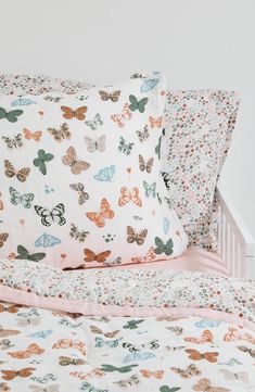 a bed topped with lots of butterflies on it's covers and pillowcases