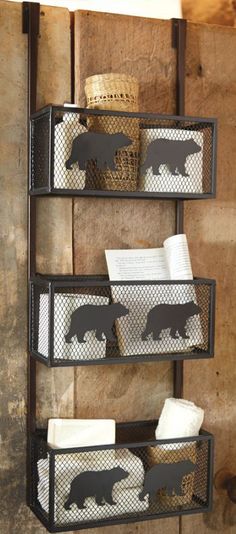 three metal baskets with black bear silhouettes on them, hanging from a rustic wall