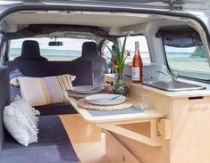 a camper van with the back door open and table set up for two people