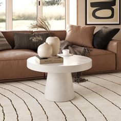 a living room with a brown couch and white table in front of large open windows