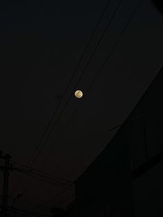 the moon is shining brightly in the dark night sky above power lines and telephone poles