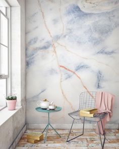 a chair sitting next to a table with a cup on it in front of a window