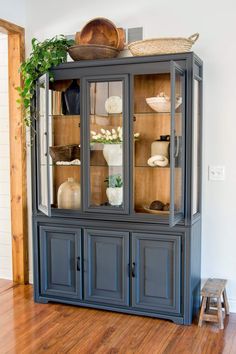 a blue china cabinet with glass doors and wooden flooring in a living room area