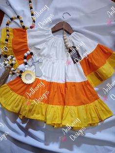 an orange, white and yellow dress with necklaces on it's neckline