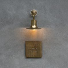 a wall light that is on the side of a building with a plaque underneath it