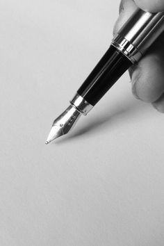 a person is holding a pen and writing on a piece of paper with the tip of their hand