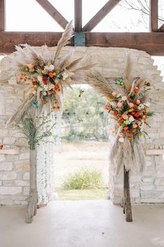 an arch decorated with flowers and feathers for a wedding ceremony at the barn in texas