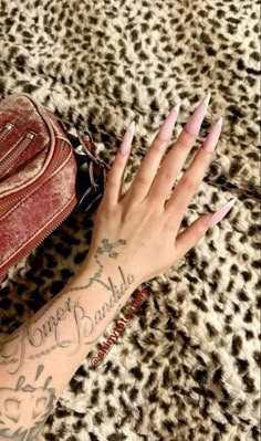 a woman's hand with some tattoos on her arm and purse next to it