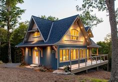 a small blue cabin in the woods at night with lights on it's windows