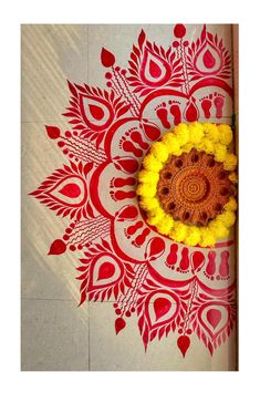 a yellow and red flower is on the floor next to a white tile with an intricate design