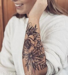 a woman with a flower tattoo on her arm and hand is smiling at the camera