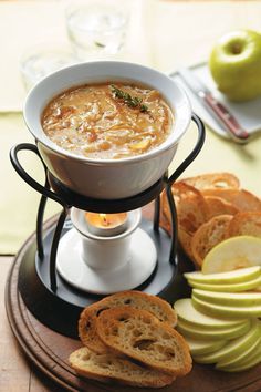 a bowl of soup on a plate with bread and apples