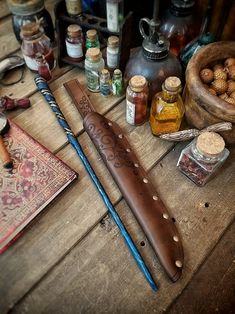 an old knife sitting on top of a wooden table next to jars and other items