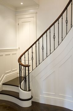 a white staircase with black handrails and wood flooring in a home's entryway