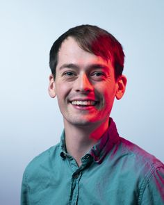 a young man smiling at the camera with red light coming from his eyes and chest