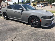 a gray dodge charger parked in a parking lot next to a gas station sign