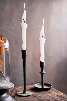 two halloween candles with ghost faces on them