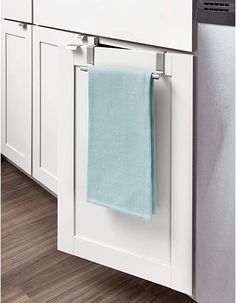 a towel hanging on the side of a white cabinet in a kitchen with wood flooring