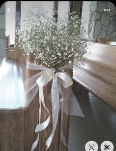 a vase filled with baby's breath sitting on top of a wooden table next to a mirror