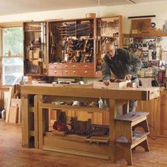 a man working in a wood shop with lots of tools on the counter and shelves