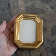 a hand holding a small gold framed object