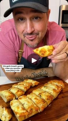 a man holding up a slice of pizza in front of some food on a cutting board