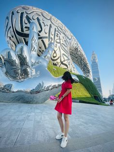 a woman standing in front of a large sculpture