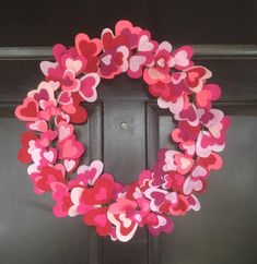 a wreath made out of paper hearts on the front door to celebrate valentine's day