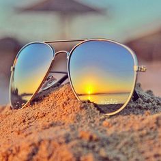 a pair of sunglasses sitting on top of a sandy beach