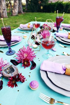 the table is set with pink and purple flowers