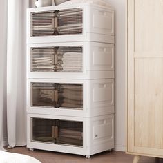 a white cabinet with four drawers and three baskets on the top, in front of a window