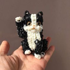 a hand holding a small black and white cat figurine