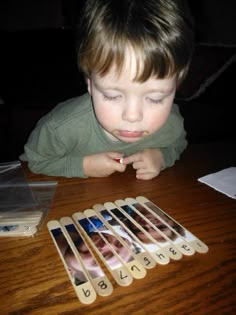 a young boy sitting at a table playing with dominos