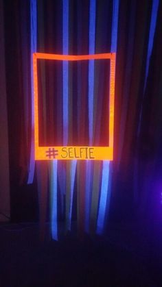 a neon sign that reads selfie in front of a window with curtains behind it