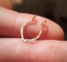 a close up of a person's hand holding a gold plated ring in their left hand