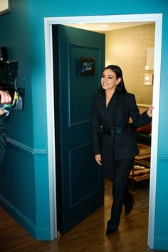 a woman in a suit walking into a blue room