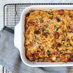 a casserole dish with meat and cheese in it on a cooling rack next to a blue towel