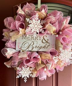 a pink wreath with white snowflakes and merry and bright written on the front door