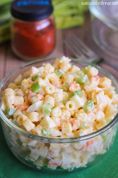 a glass bowl filled with macaroni salad on top of a green tablecloth