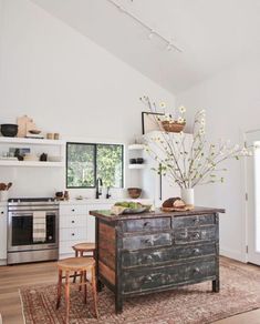 a kitchen with white walls and wooden floors, an old dresser is on the far side of the room