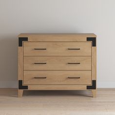 a wooden dresser sitting on top of a hard wood floor next to a white wall