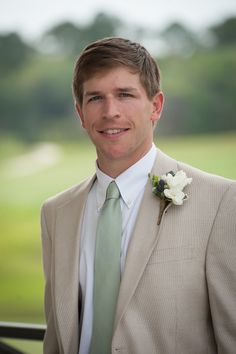 a man in a suit and tie posing for a photo with a flower on his lapel