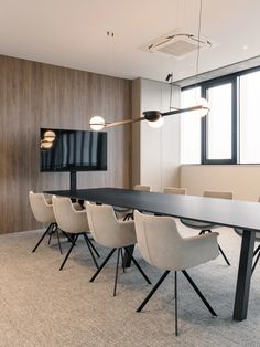 an empty conference room with chairs and a flat screen tv mounted on the wall above it