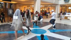 several people are walking around in a shopping mall, one is wearing a white veil