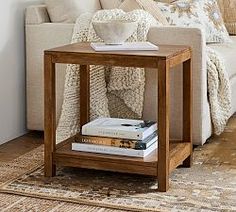 a living room with a couch, coffee table and books on the floor in front of it